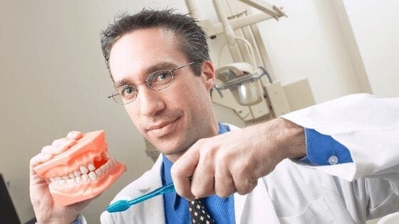 Dentist holding a set of teeth for dental hygiene sample.