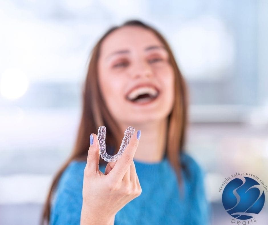 Young girl happy holds Invisalign aligner